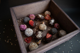 手工制作的糖免费的和谷蛋白免费的水果和巧克力糖果木盒子和黑色的背景手工制作的水果和巧克力糖果木盒子