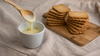 碗与浓缩牛奶和饼干的背景碗与浓缩牛奶与木勺子和饼干的背景