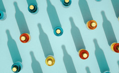 前视图几个玻璃瓶与金属帽站绿松石蓝色的背景啤酒瓶各种各样的颜色与长阴影复古的喝瓶概念