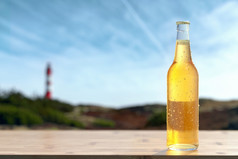单瓶冷啤酒站木酒吧露湿的玻璃瓶与空白白色标签回来光放松海滩概念含酒精的饮料和点心概念