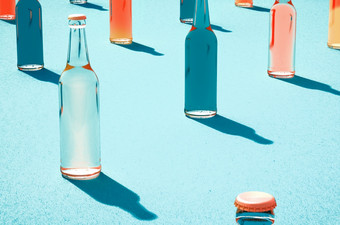 <strong>原型</strong>玻璃啤酒瓶与帽和没有标签阴影光蓝色的表面复古的喝瓶概念