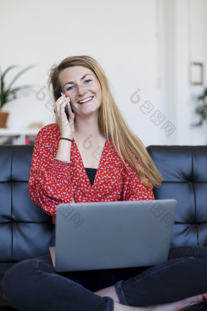 企业家女人穿蓝色的衬衫工作与移动PC坐着沙发上首页