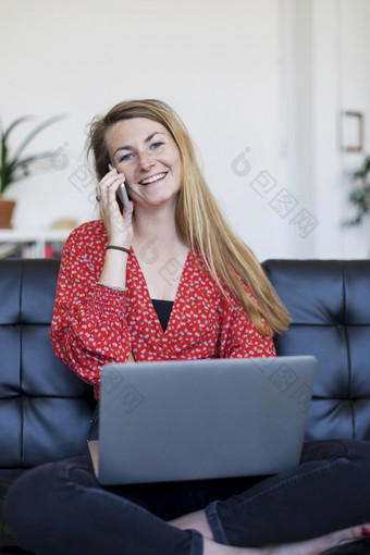 <strong>企业</strong>家女人穿<strong>蓝色</strong>的衬衫工作与移动PC坐着沙发上首页
