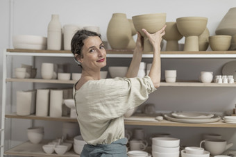 女<strong>陶艺</strong>家在室内持有手工制作的粘土产品概念陶器