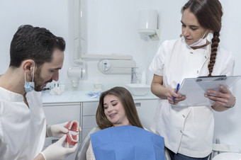 年轻的男人。牙医显示牙科下巴模型女病人牙医rsquo办公室微笑女人牙医坐着牙医椅子牙科