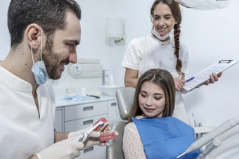 年轻的男人。牙医显示牙科下巴模型女病人牙医rsquo办公室微笑女人牙医坐着牙医椅子牙科