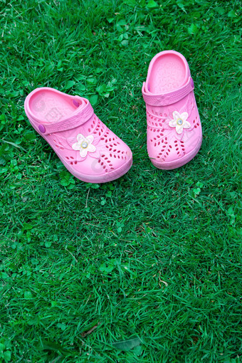 粉红色的孩子拖鞋绿色草坪上复制空间前视图位于前的框架垂直概念团结与自然模拟为孩子们商店产品妈妈。博客育儿杂志