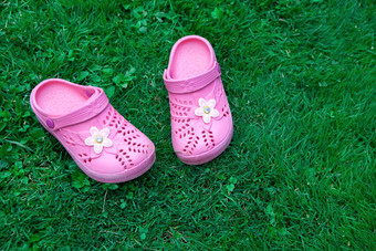 粉红色的孩子拖鞋绿色草坪上复制空间前视图位于一边框架水平概念团结与自然模拟为孩子们商店产品妈妈。博客育儿杂志
