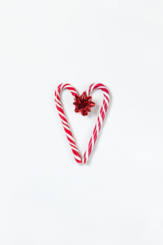 圣诞节作文心使两个焦糖糖果拐杖和红色的弓白色背景节日最小的风格平躺为问候卡邀请社会媒体垂直取向