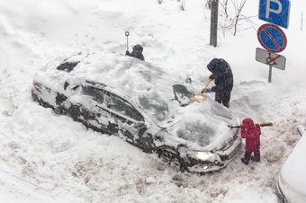 认不出来人是清算白雪覆盖的车成暴风雪孩子们帮助他们的父亲清晰的雪从车在那里强大的暴雪外冬天例程和问题概念