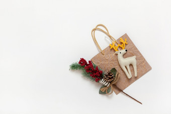 金圣诞节礼物袋白色感觉玩具鹿与黄色的角嫩枝与红色的浆果和针白色背景复制空间节日新一年销售购物概念平躺前视图