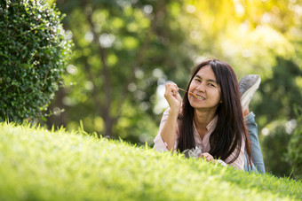 放松年轻的美丽的女人与微笑脸享受吃猪肉坚持的公园<strong>时间</strong>放松后工作horizontalblurredbackgroundFilm<strong>效果</strong>