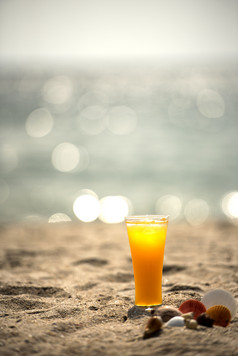 新鲜的橙色汁的海滩与蓝色的天空背景和海散景夏天概念