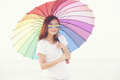 美丽的女人持有彩虹色彩斑斓的伞旅行概念
