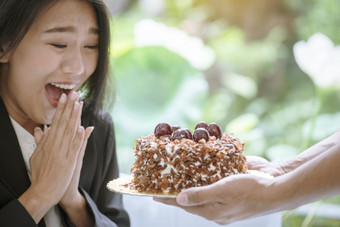 快乐女人吃蛋糕美味的甜蜜的甜点巧克力咖啡馆甜蜜的花俏的蛋糕得到了惊喜生日礼物糖美味的板咖啡商店女人坐着舒适的沙发持有甜蜜的蛋糕