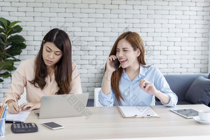 快乐企业家亚洲女商人使用智能手机处理谈判为启动业务两个合作伙伴享受好新闻从智能手机团队合作协作亚洲女人工作在一起