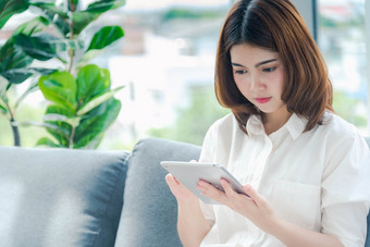 亚洲女人使用智能手机阅读在线社会媒体购物在线网站智能手机与微笑脸幸福亚洲女人持有手机检查邮件读博客视频博客社会媒体