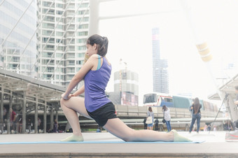 体育运动健身女人伸展运动身体锻炼现代城市穿健康运动服装外年轻的女人锻炼户外锻炼明亮的阳光明媚的外健康的健康生活方式女人概念