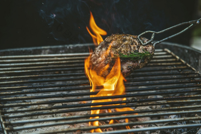 烧烤热烤肉与火火焰热烧烤烹饪晚餐燃烧从木炭烤牛排烧烤与火和吸烟烹饪外牛肉烧烤户外为聚会，派对西方食物概念