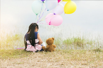 快乐孩子拥抱泰迪熊持有空气气球绿色公园操场上泰迪熊最好的朋友为小孩子们可爱的女孩自闭症快乐玩在一起持有色彩斑斓的氦气球操场上