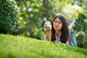 放松美丽的亚洲女人微笑脸说谎<strong>下</strong>来绿色草场在<strong>户外</strong>花园公园享受自然早....自由生活方式女人呼吸新鲜的空气绿色公园春天草坪上在<strong>户外</strong>