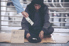女人帮助手无家可归的人人贫困乞丐男人。持有手问为钱工作和希望帮助无助的脏城市坐着街道绝望的乞丐城市概念