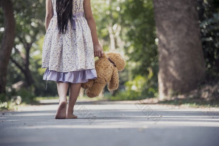伤心女孩拥抱泰迪熊悲伤独自一人绿色花园公园孤独的女孩感觉伤心不开心走在户外与最好的朋友玩具自闭症孩子玩泰迪熊最好的朋友家庭暴力概念