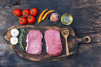 生肉牛肉牛排有机新鲜的成分木董事会表格背景厨房与迷迭香盐大蒜番茄黑色的胡椒橄榄石油肉牛肉木板为牛排生肉