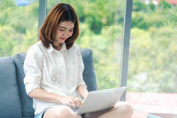 女人工作从首页移动PC在线会议首页办公室企业家亚洲业务女人使用笔记本移动PC坐沙发技术新正常的生活方式快乐女人打字键盘移动PC