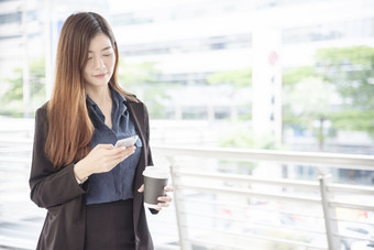 业务女人使用智能手机购物在线调用发短信消息互联网技术生活方式亚洲女人使用手机走城市街聪明的电话聪明的自信女人现代城市