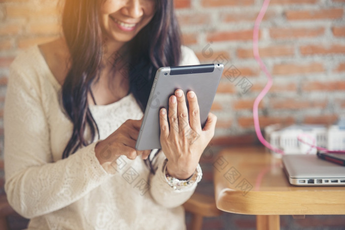亚洲女人使用数字平板电脑购物在线调用发短信消息互联网技术生活方式与微笑脸亚洲女人触摸聪明的平板电脑焦点手使用移动应用程序首页办公室