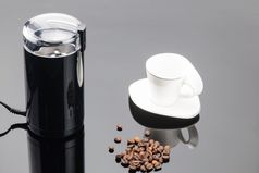黑色的咖啡磨床与一些咖啡豆子和杯的灰色镜子背景复制空间咖啡磨床与咖啡豆子和杯的灰色镜子背景复制空间