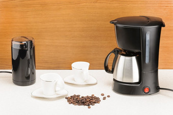 电咖啡机与不锈钢钢咖啡能和一些咖啡豆子的木和大理石背景咖啡机与能和一些咖啡豆子的木和大理石背景