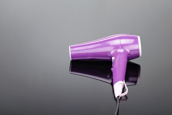 粉红色的电手持头发干燥机为头发沙龙理发师商店的灰色镜子背景与复制空间粉红色的头发干燥机的灰色镜子背景与复制空间