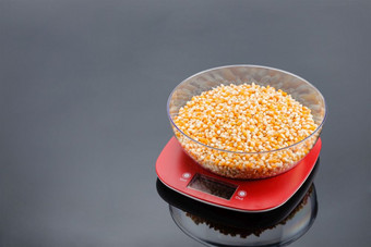 玉米透明的碗红色的塑料电子规模灰色镜子背景复制空间玉米碗电子规模灰色镜子背景与复制空间