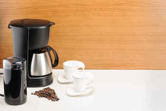 电咖啡机与不锈钢钢咖啡能和一些咖啡豆子的木和大理石背景复制空间咖啡机与能和一些咖啡豆子的木和大理石背景复制空间