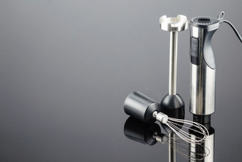 黑色的塑料电手搅拌机与不锈钢钢身体和附件的灰色镜子背景复制空间搅拌机与附件的灰色镜子背景