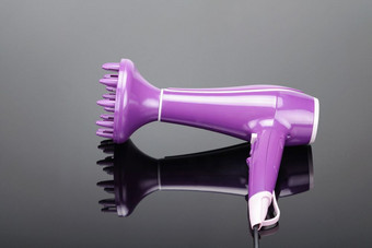 粉红色的电手持头发干燥机与传播为头发沙龙理发师商店的灰色镜子背景与复制空间粉红色的头发干燥机与传播的灰色镜子背景与复制空间