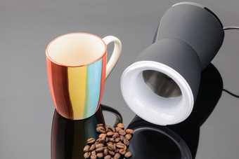 黑色的咖啡磨床与一些咖啡豆子和粘土杯子的灰色镜子背景复制空间咖啡磨床与咖啡豆子和杯子的灰色镜子背景复制空间