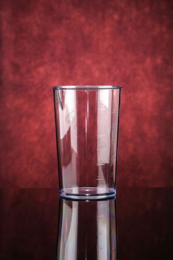 透明的测量玻璃为黑色的塑料电手搅拌机的红色的镜子背景透明的测量玻璃为搅拌机的红色的镜子背景