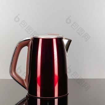 画红色的颜色不锈钢钢无线电水壶与棕色（的）塑料处理的灰色镜子背景与复制空间红色的不锈钢钢水壶的灰色镜子背景