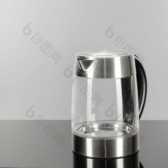 玻璃不锈钢钢无线电水壶与黑色的塑料处理的灰色镜子背景与复制空间玻璃不锈钢钢水壶的灰色镜子背景