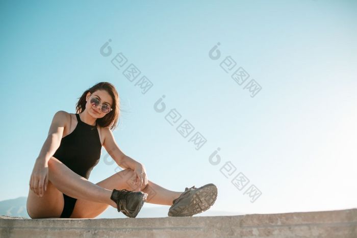 年轻的浅黑肤色的女人女孩黑色的运动鞋黑色的短裤和黑色的短前坐着的屋顶高建筑