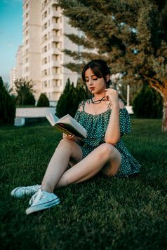 年轻的高加索人女孩古董复古的衣服读取书的草坪上在日落