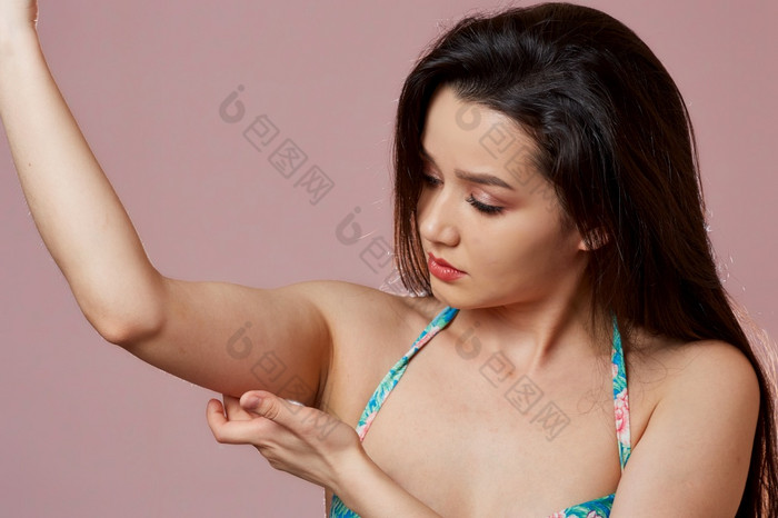 年轻的美丽的纤细的亚洲女孩泳衣显示她的手臂肱二头肌粉红色的孤立的背景