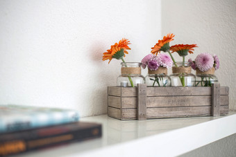 木盒子与橙色和粉红色的花白色架子上白色背景现代设计生活房间木盒子与橙色和粉红色的花白色架子上白色背景现代设计