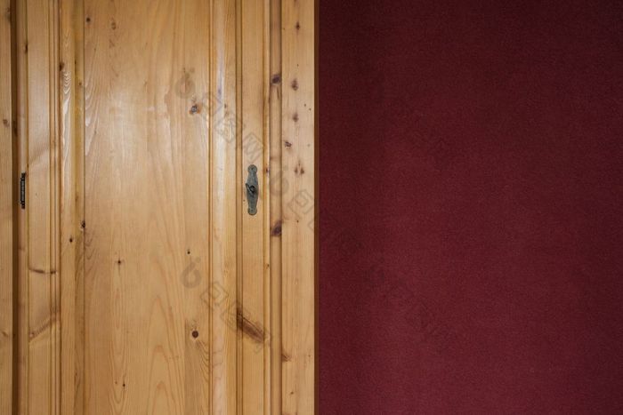 棕色（的）木衣橱门关闭与红色的波尔多墙首页纹理棕色（的）木衣橱门关闭与红色的波尔多墙