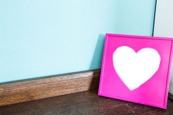 粉红色的心图片框架木表格与蓝色的墙背景空间为文本特写镜头粉红色的心图片框架木表格与蓝色的墙背景空间为文本