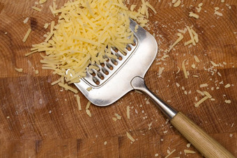 金属奶酪刨丝器和奶酪木切割董事会特写镜头金属奶酪刨丝器和奶酪木切割董事会