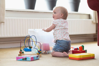 婴儿玩独自一人与玩具地毯的地板上首页混乱的婴儿玩独自一人与玩具地毯的地板上首页